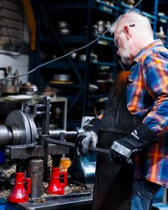 manually trimming a metal part on a lathe